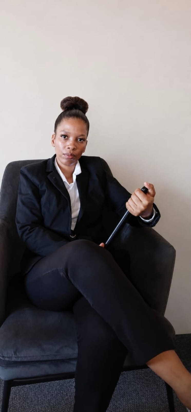 Portrait of the founder of Ntheba Distributors, seated in a dark armchair and wearing a black blazer